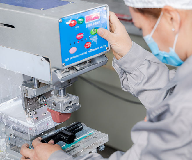 a female worker is printing logo on the product with the printing machine