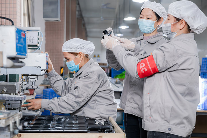 two female workers are discussing the product while another one is doing product printing