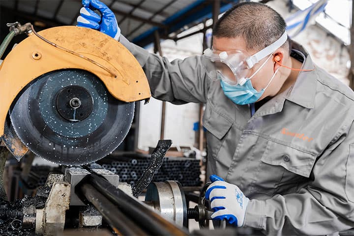 a male worker wearing safety goggle is processing metal post